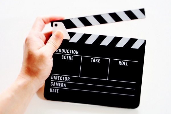 映画撮影で使われるカチンコ（クラッパーボード）を持つ手元の写真