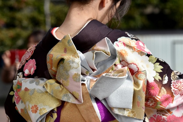 花柄の振袖と帯結びを身に着けた女性の後ろ姿